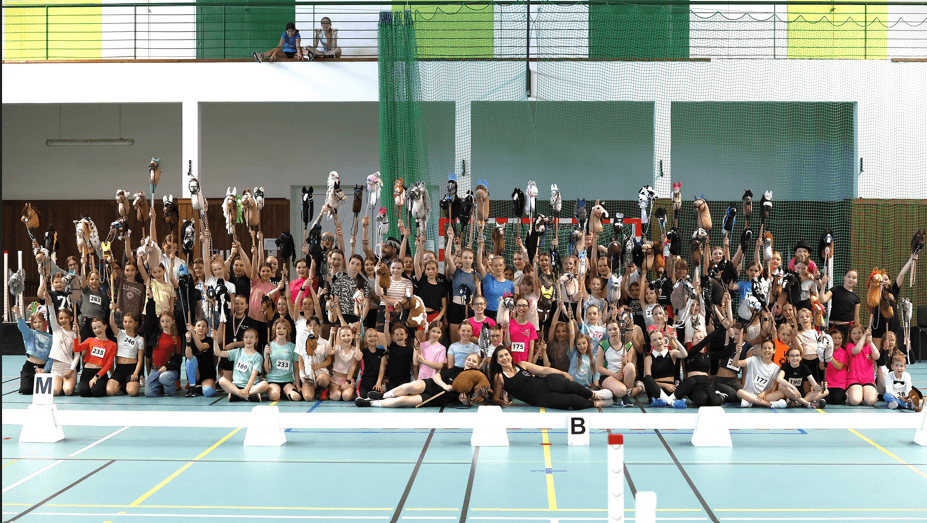Group of children and teenagers holding Hobby Horses at an indoor Hobby Horsing competition