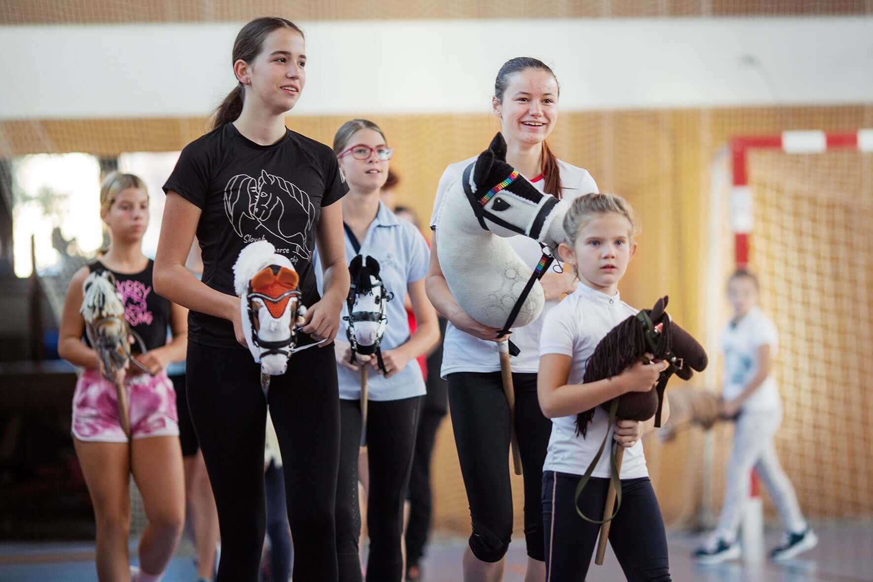 Children and teenagers holding Hobby Horses during an indoor Hobby Horsing event