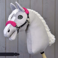 The Hobby Horse LarDen "Black halter with rose fur - leatherette" features a light gray plush head, rose fur accents, white yarn mane, and black halter on a wooden stick, set against a wooden plank background.