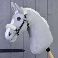 The Hobby Horse LarDen Black halter with fur - leatherette, a grey plush horse with a white mane and black halter on a wooden stick, stands against a wooden panel background.