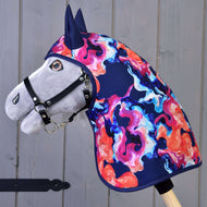 The Hobby Horse LarDen "Raincoat Rainbow" features a plush hobby horse with a black halter and a vibrant winter softshell mane and neck cover in blue, pink, orange, and purple patterns, shown against a gray wooden background.