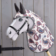 A Hobby Horse LarDen fabric hobby horse with a gray face, black bridle, and colorful paisley cover stands against wooden paneling, wearing a matching Raincoat Fairy Blue softshell for added charm and protection.
