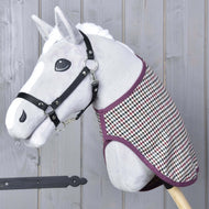 A gray hobby horse toy by Hobby Horse LarDen, featuring a black halter and the Blanket western Colorado, mounted on a wooden stick and set against a gray wooden wall.