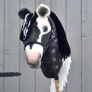 Front view of the black and white Hobby Horse Domino with pink muzzle, blue eyes and black yarn forelock
