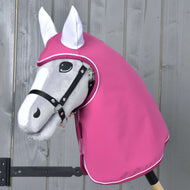 The Raincoat Larden by Hobby Horse LarDen, a gray hobby horse toy with a black bridle and pink hood for weatherproofing, is displayed in front of a wooden wall.