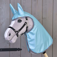 A Hobby Horse LarDen gray hobby horse with a black bridle, large felt eyes, and a Raincoat Light Blue hood with matching ears, displayed against a wooden wall.