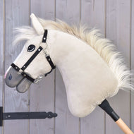 The Hobby Horse LarDen "Hobby Horse Pixie with Black Halter" features a plush beige Akhal-Teke design with a white mane, black halter, and wooden stick, showcased against a light gray wooden wall.