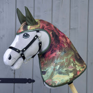 The Raincoat Galaxy by Hobby Horse LarDen features a realistic grey hobby horse with a black bridle and a marbled green, red, and cream all-weather raincoat-style head and neck cover, displayed against a wooden background.