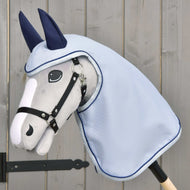The Hobby Horse LarDen Raincoat Luméa features a plush gray stick horse with a black bridle, blue raincoat, and navy ear covers, displayed against a light wooden background.