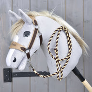 The Set LarDen Exclusive Braun by Hobby Horse LarDen features a plush gray hobby horse with a white mane, brown bridle, fleece noseband, and braided rope reins on a wooden stick, shown against a gray wooden wall.