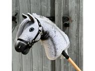 The Hobby Horse LarDen Naivy, size S, features a gray and white Appaloosa design with a black halter and white mane, mounted on a stick and shown before a weathered wooden door.
