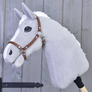 A gray plush Hobby Horse LarDen with white mane and nose markings features a brown leatherette Halter, mounted on a wooden stick, and is displayed against a gray wooden wall.