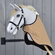 A gray fabric hobby horse from Hobby Horse LarDen, featuring a black bridle and the Travel Rug Paris, is mounted on a wooden stick and placed in front of a wooden fence.