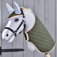 The Hobby Horse LarDen Set Moos features a gray hobby horse with black bridle, green quilted blanket, and light blue ear bonnet on a wooden stick, shown against a gray wooden wall.