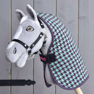 A handmade gray hobby horse with a black bridle, dressed in the Hobby Horse LarDen "Stable Blanket Green," is displayed against a wooden background.
