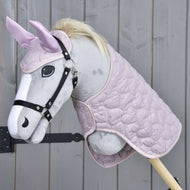 The Hobby Horse LarDen Set Sweetest Heart features a plush hobby horse with a light gray face, black bridle, pale mane, pink ears with ear bonnet, and quilted pink blanket, displayed on a wooden background.
