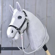 The Hobby Horse LarDen Reins Tizian features a plush gray hobby horse with a black bridle and handmade reins on a wooden stick, pictured against a light wooden panel background.