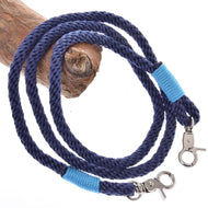 The Rope set Dark Blue by Hobby Horse LarDen features a coiled dark blue leash with metal clasps at both ends, each wrapped with bright blue thread, and is displayed on a light brown wooden branch—a stylish riding accessory.