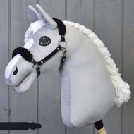 The Hobby Horse LarDen Black Halter with Black Fur features a plush, light gray horse with a black leatherette halter and large embroidered eyes, shown against a gray wooden background.