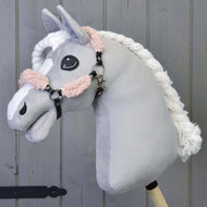 The Hobby Horse LarDen Black Halter with Old Rose Fur Complete – leatherette is a plush hobby horse with a light gray head, white braided mane, and black halter, mounted on a wooden stick against a wooden panel background.