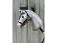 The Hobby Horse LarDen Midnight Blue with Black Halter (size S) is mounted on a wooden stick and displayed in front of a weathered wooden door.