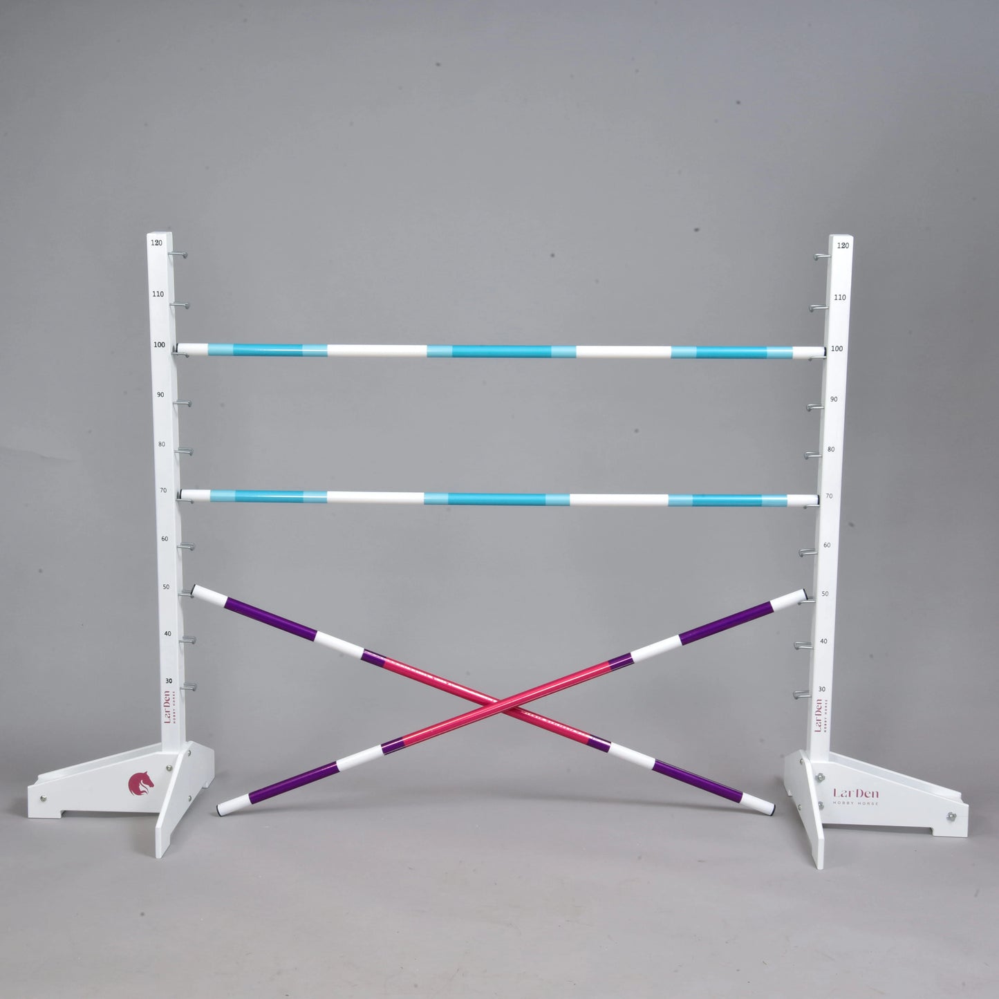 The Hobby Horse LarDen Jump 120 cm / 47 inch with Extra Poles includes two white standards, three blue and white adjustable poles, two crossed purple and white poles, and is ideal for indoor or outdoor hobby horsing. Shown against a plain gray background.
