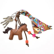 A set of keys on a keyring features the Hobby Horse LarDen Keychain Horse Brown, colorful beads, and a vibrant patterned scarf tied in a bow.