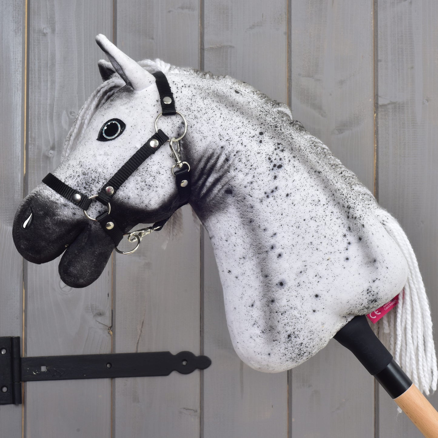 The Hobby Horse LarDen Hobby Horse Naivy with Black Halter - size S, featuring a realistic gray and black stallion head with a black halter, is displayed in front of a gray wooden wall.