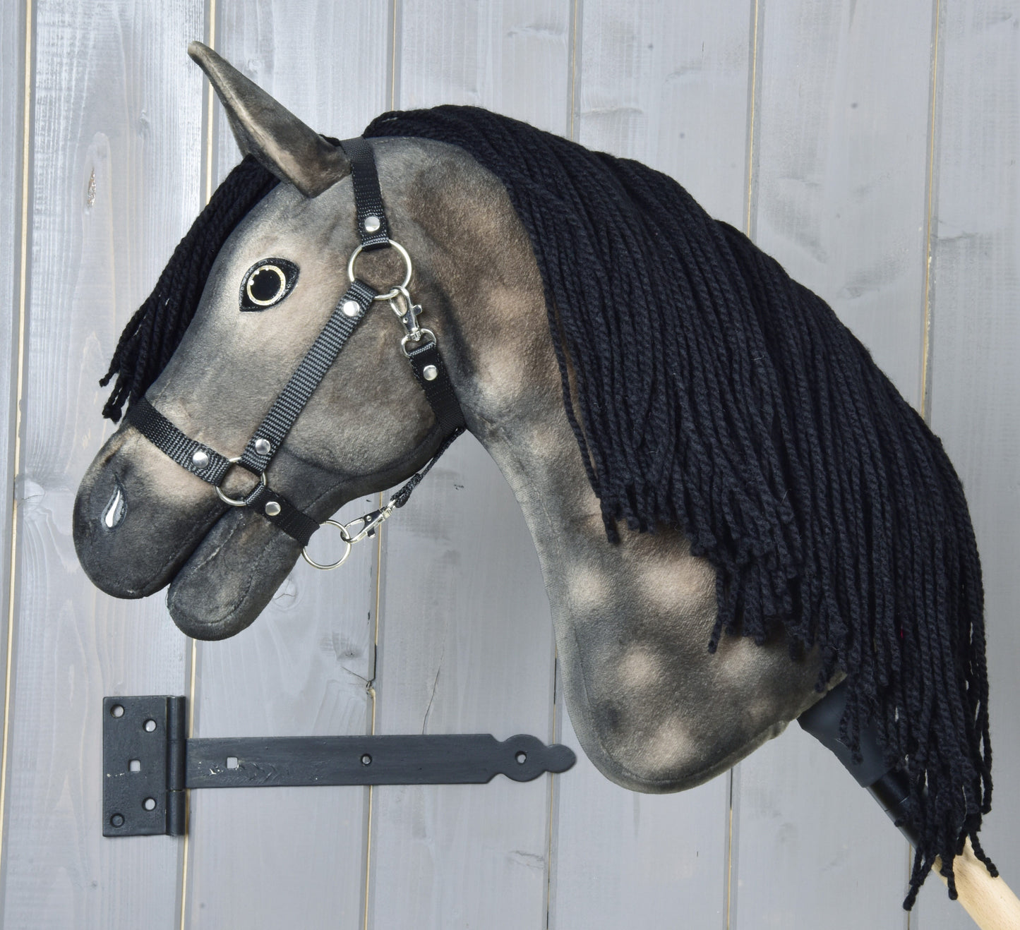 Side view of Hobby Horse Stormy with Black Halter by Hobby Horse LarDen, showing the silvery dapple grey coat, charcoal shading and thick black mane with a black halter on a wooden stick.