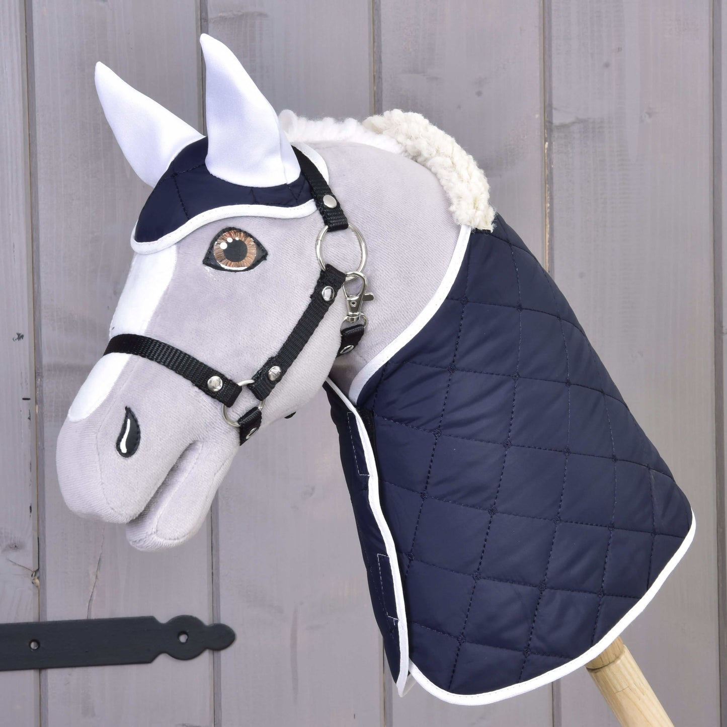 The Set Thermo Blue by Hobby Horse LarDen features a plush hobby horse head with white ears, a harness, and a quilted navy blue blanket—ideal as a charming horse décor accent.