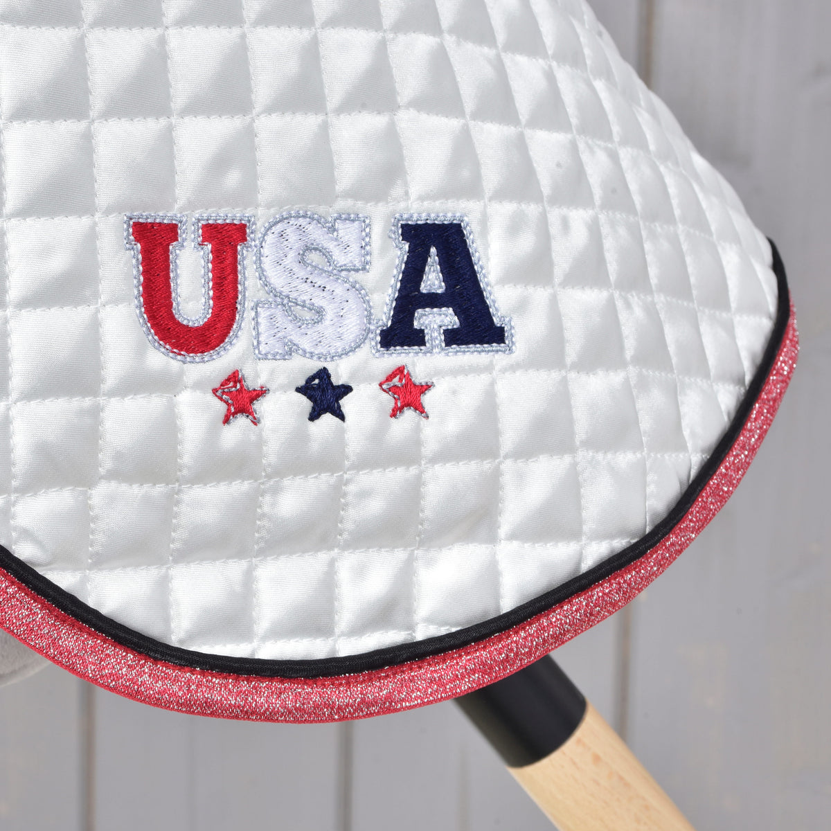 Close-up of red, white and navy USA embroidery with three stars on the white quilted Hobby Horse blanket
