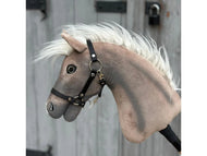 The Hobby Horse LarDen "Happy Boy with Black Halter" features a realistic light brown Hannoveraner look, white mane, black halter, and expressive eyes, shown in front of a gray wooden door with black metal accents.