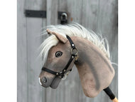 The Hobby Horse LarDen "Happy Boy with Black Halter" is a gray and white Hannoveraner Pferd hobby horse featuring a black halter and white mane, displayed against a wooden background with metal hinges and a latch.