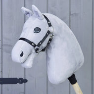 A light grey “Build your horse” handmade hobby horse by related_to_12441055625556, featuring a black bridle and mounted on a wooden stick, is positioned against a wooden grey wall background.