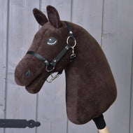 Here’s a rewritten version of the sentence using your product data: The Build your horse by related_to_12441055625556 is a customizable brown plush hobby horse head with a black bridle and reins, mounted on a wooden stick and displayed against a gray wooden wall.