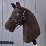 A “Build your horse” custom hobby horse by related_to_12441055625556 features a dark brown plush head with black manes and a black bridle, attached to a wooden stick and displayed in front of a gray wooden wall.