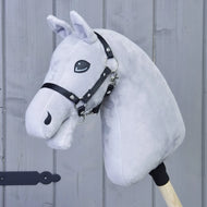 A light grey plush hobby horse head on a wooden stick, featuring a black bridle, stands before a gray wooden wall—ideal for anyone interested in the “Build your horse” product by related_to_12441055625556, or for customizing your own hobby horse to inspire imaginative play.