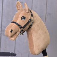 A plush Build your horse by related_to_12441055625556, featuring light brown caramel-colored fur, a black bridle, and stitched eyes, rests against a wooden background with beautifully crafted chocolate manes that add extra charm.