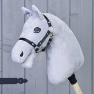 A “Build your horse” custom hobby horse by related_to_12441055625556, featuring light grey plush, striking turquoise eyes, and black reins, is mounted on a wooden stick and displayed in front of a vertical wooden panel wall.
