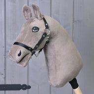 The "Build your horse" custom hobby horse from related_to_12441055625556 features a gray plush head with striking blue eyes and a black bridle, mounted on a wooden stick, and is displayed in front of a gray wooden door.