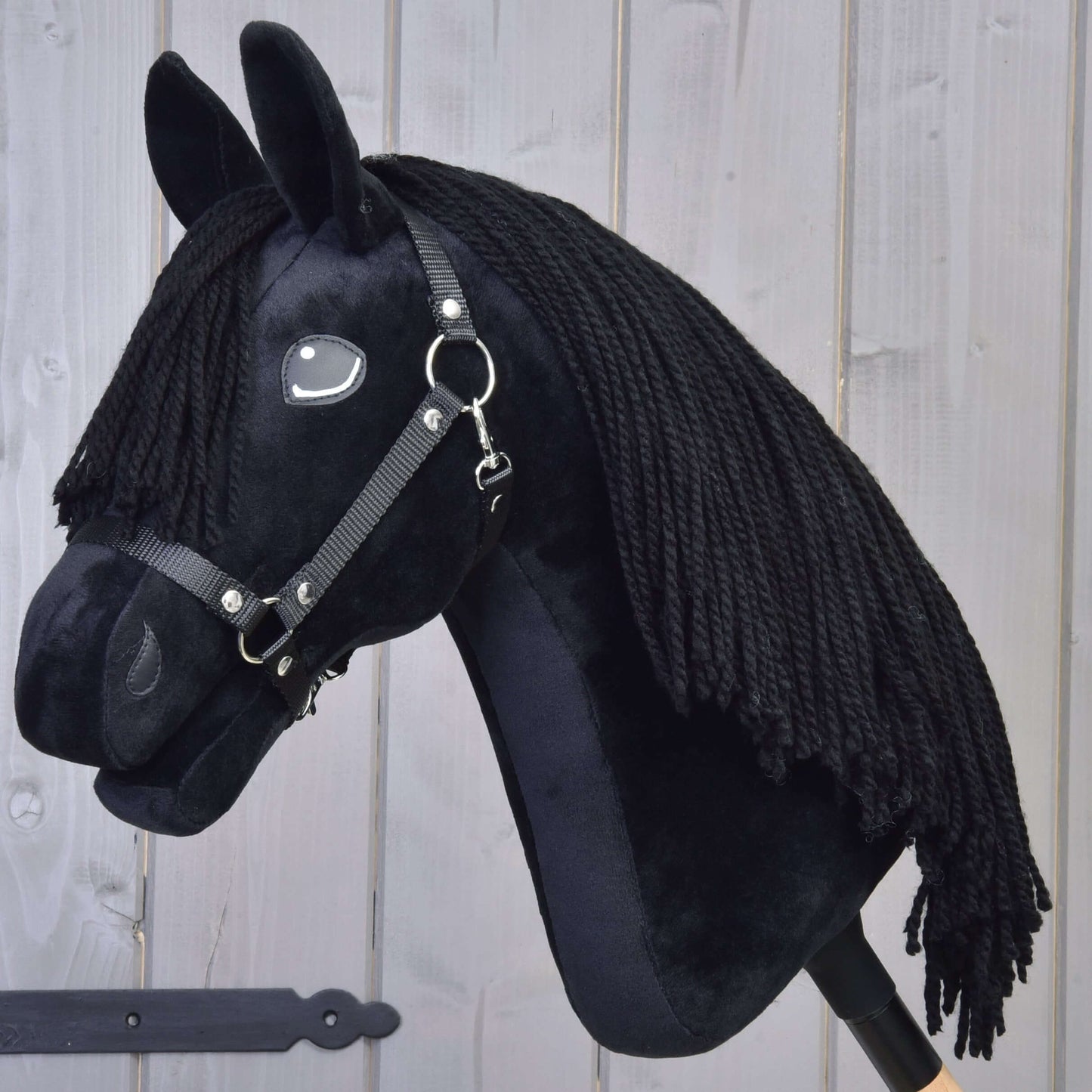 Black plush Hobby Horse Mahal with Black Halter featuring yarn mane against wooden background